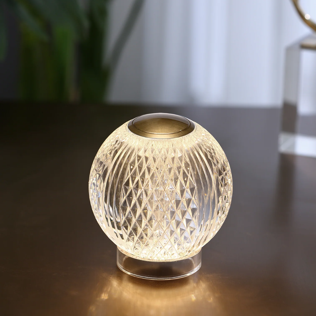Crystal glass portable LED table lamp with diamond-cut texture and warm ambient glow, displayed on a dark modern surface with soft background decor.