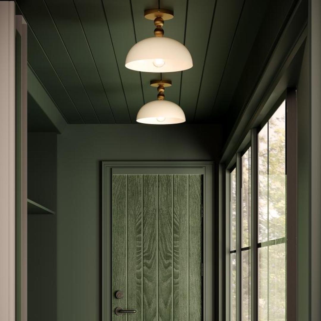 Brass LED picture light mounted above a framed landscape painting, illuminating artwork in a warm-toned hallway with wooden cabinetry and floral decor.