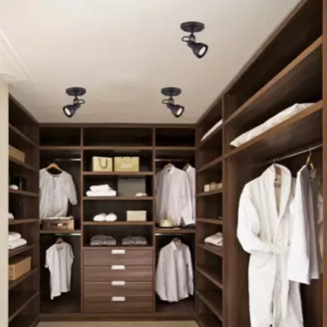 Modern walk-in closet with dark wood shelving and ceiling-mounted directional track lights, designed for organized clothing and accessory storage.