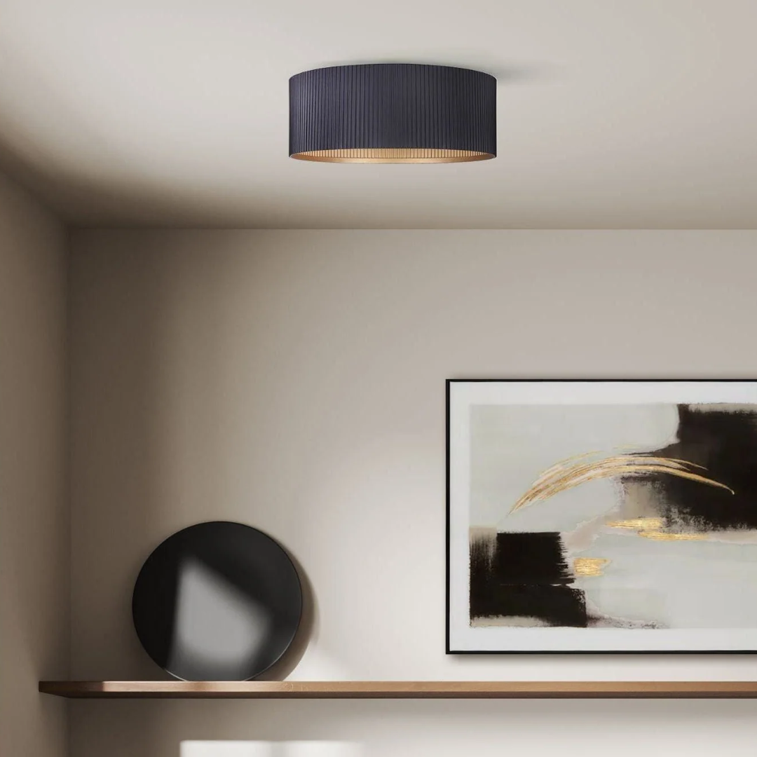 Modern flush mount ceiling light with a black pleated drum shade, featured in a minimalist interior with neutral walls, abstract artwork, and a wood floating shelf.