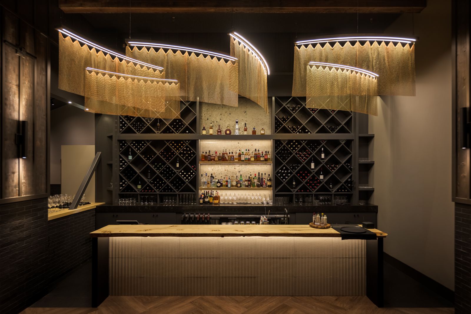 Custom chandelier lighting above the bar at Kettle Valley Steakhouse in Big White Ski Resort with modern hospitality lighting design.