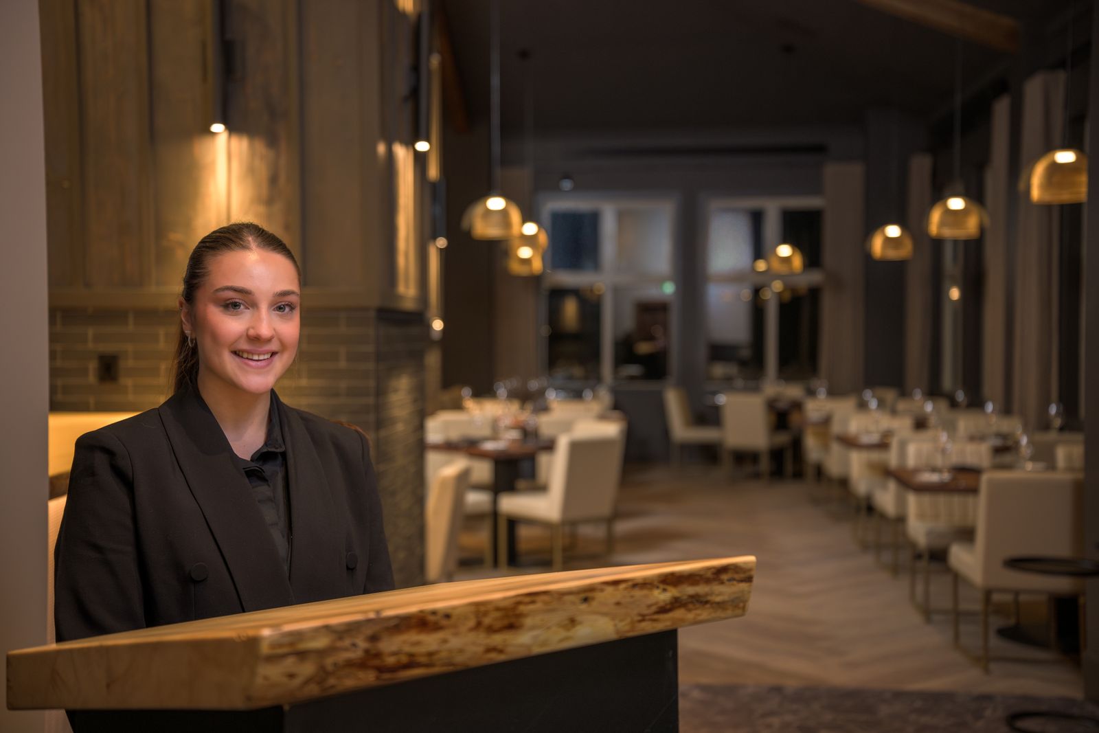 Restaurant host stand at Kettle Valley Steakhouse featuring warm ambient lighting and modern pendant fixtures at Big White Ski Resort.