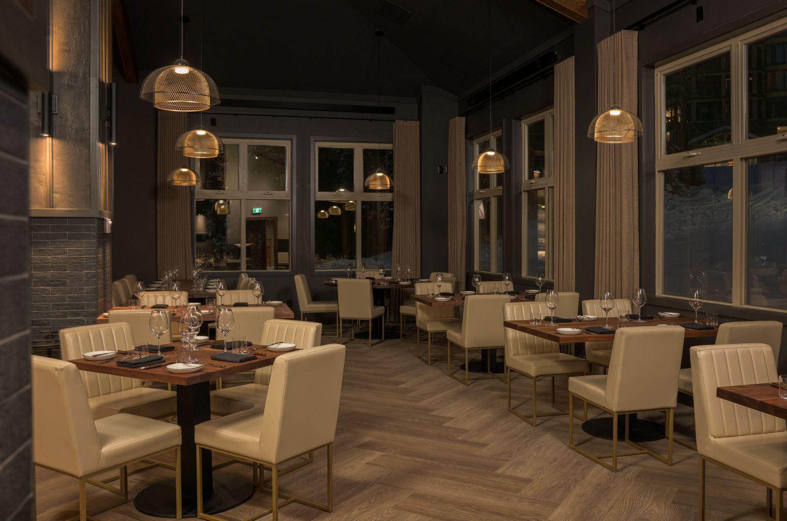 Contemporary pendant lighting illuminating dining tables inside Kettle Valley Steakhouse at Big White Ski Resort.